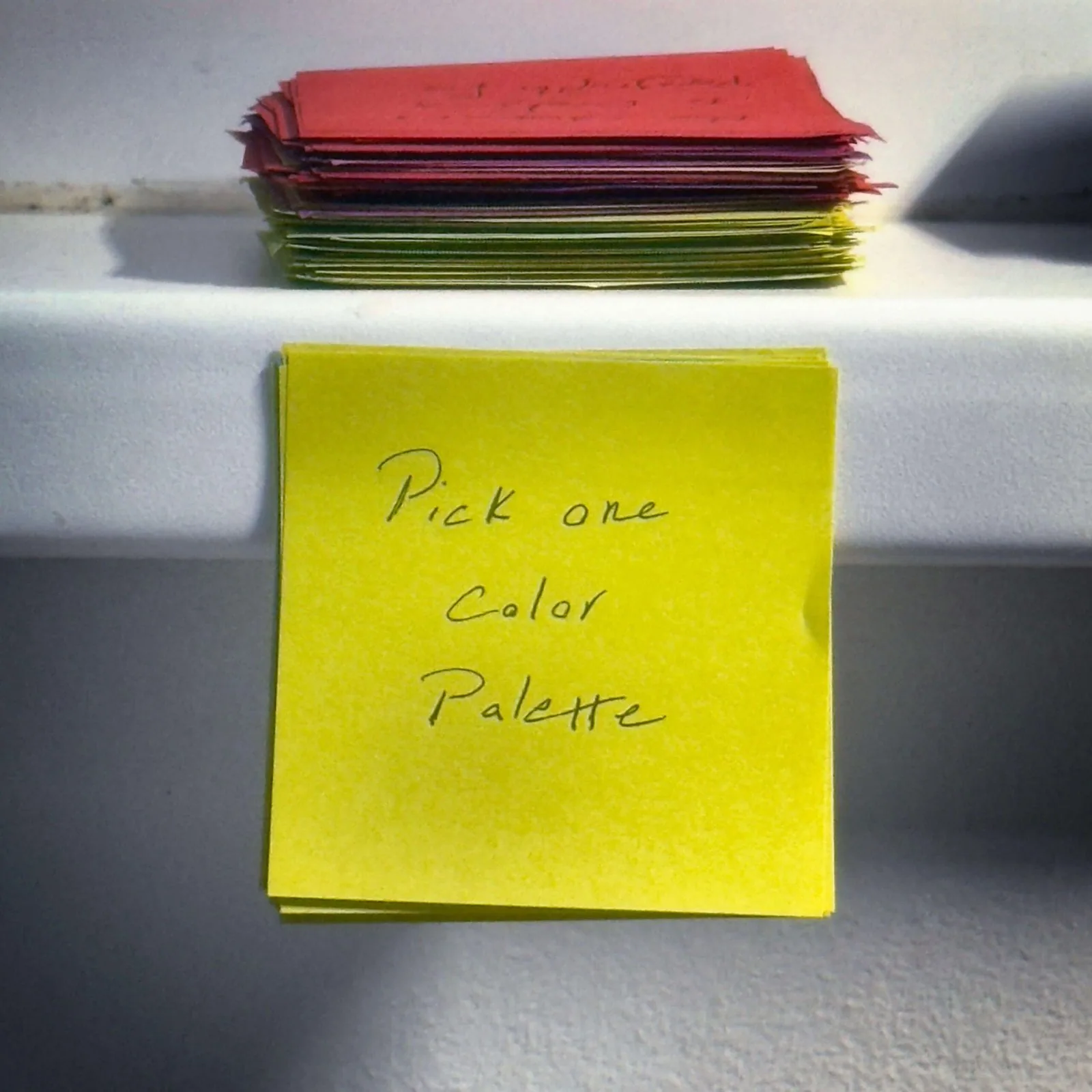 Yellow sticky note with 'Pick one Color Palette' written on it, demonstrating the next step method for overcoming analysis paralysis on creative projects